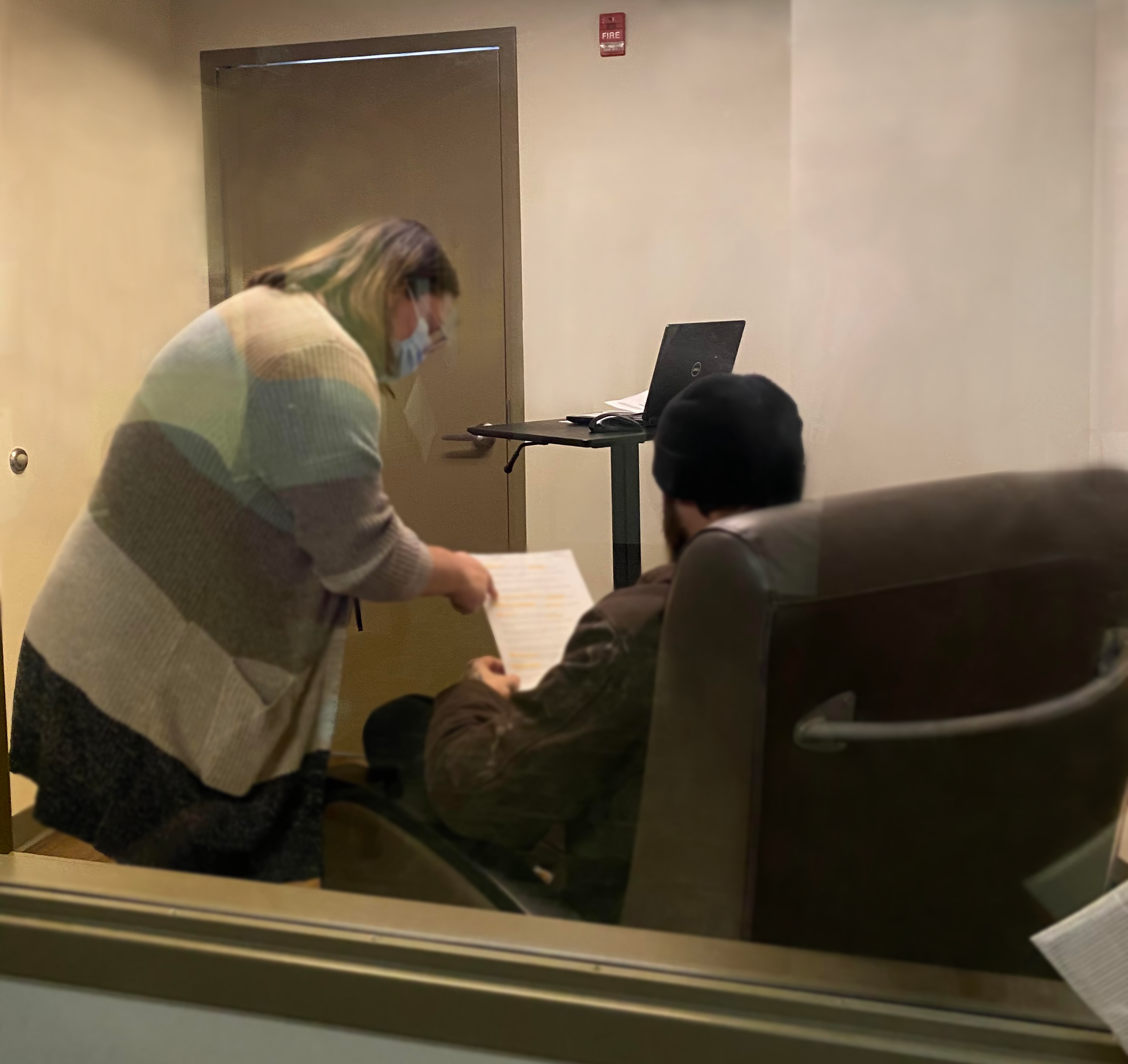 Woman handing man in chair papers